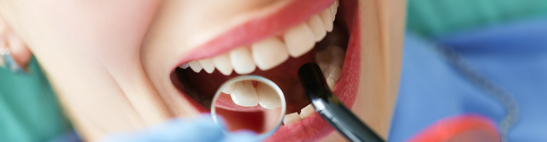 Gloved hands using dental tools in woman's mouth.